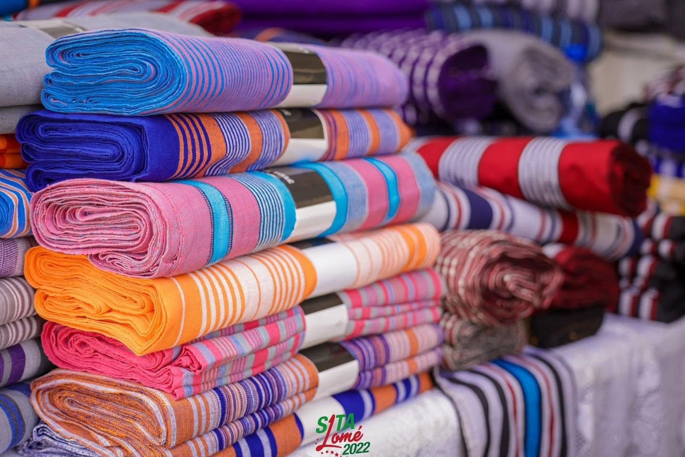 Piles de pagnes et tissus africains colorés exposés lors du SITA Lomé 2022